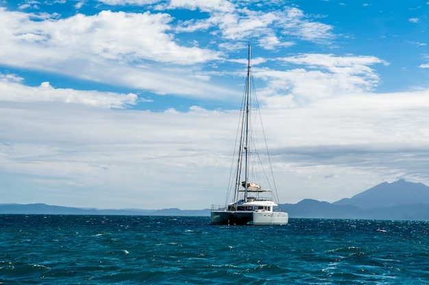 A sailboat sails in the distance against a mountain backdrop